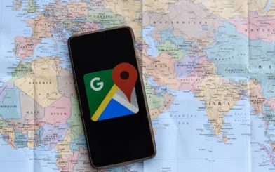 A smart phone with Google Maps open is laying on top of a map of the world.